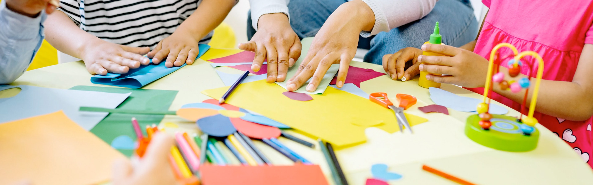 Kinder basteln mit buntem Papier am Tisch