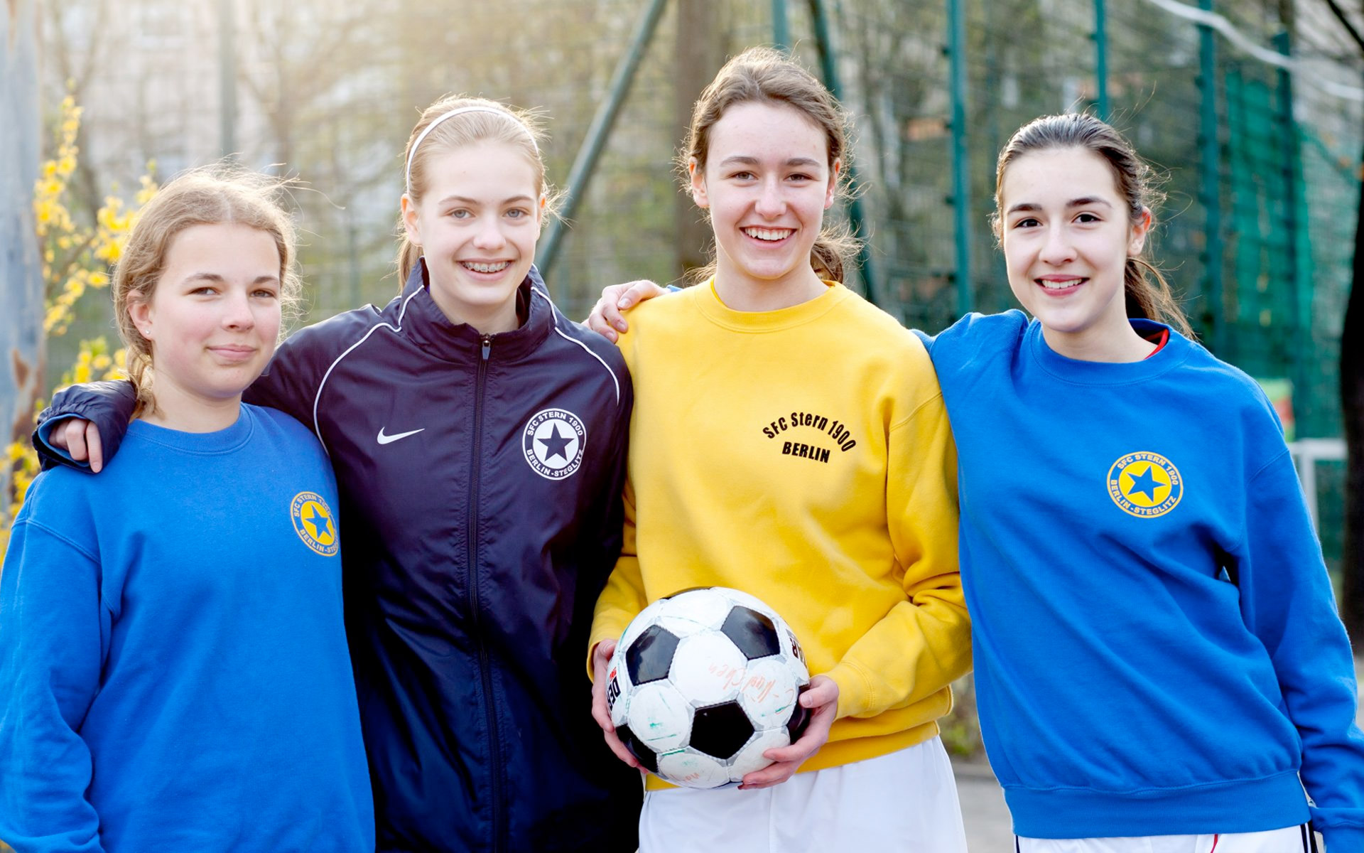 Gruppenfoto von vier Mädchen in Fußballsachen mit Ball