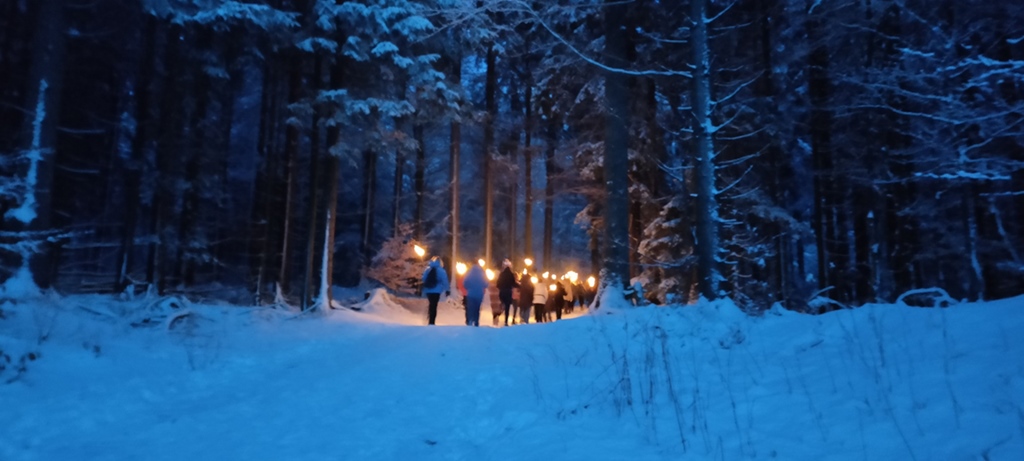 Fackelwanderung durch den verschneiten Wald